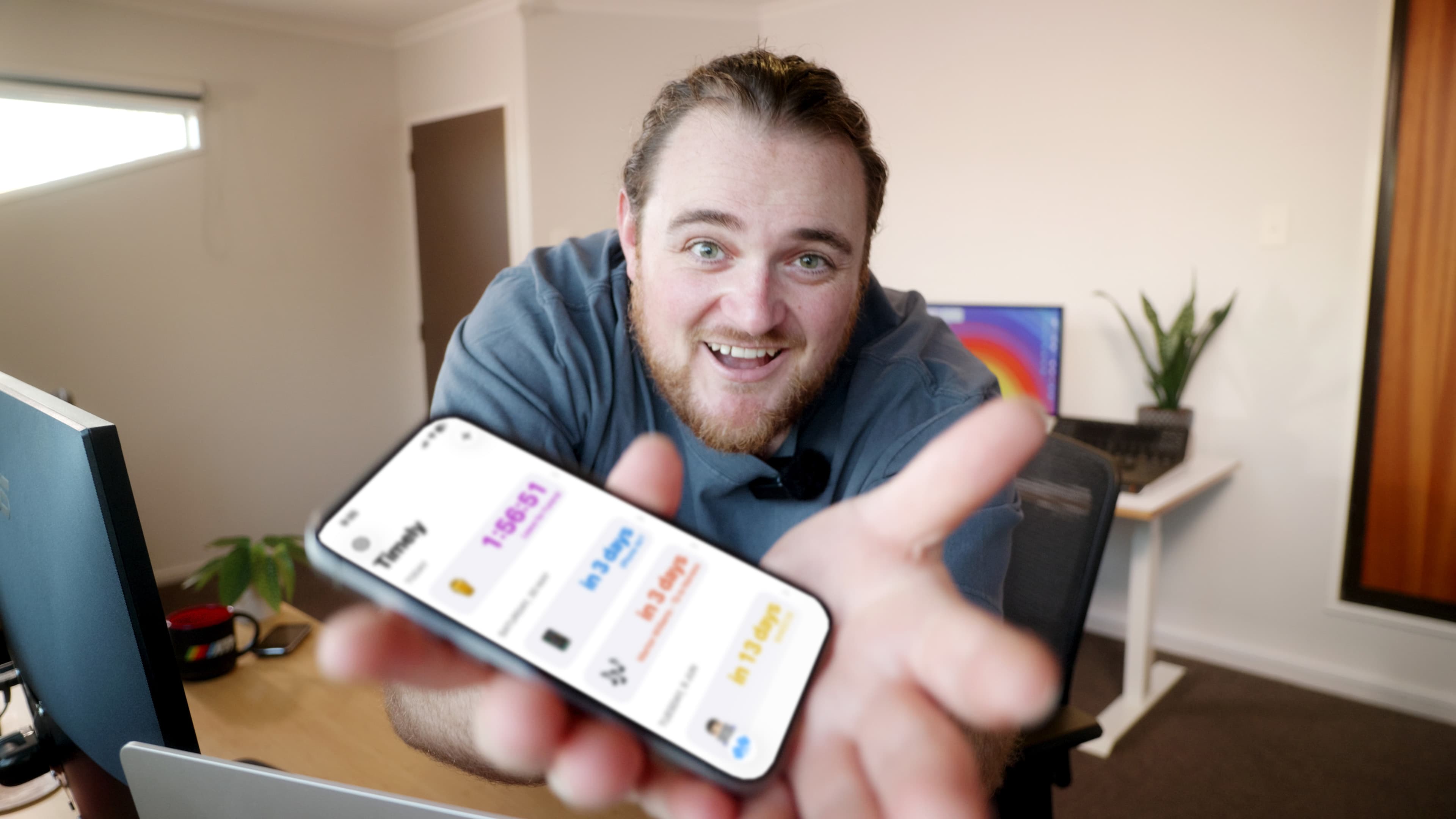 Rowan holding an iPhone displaying Timely toward the camera.